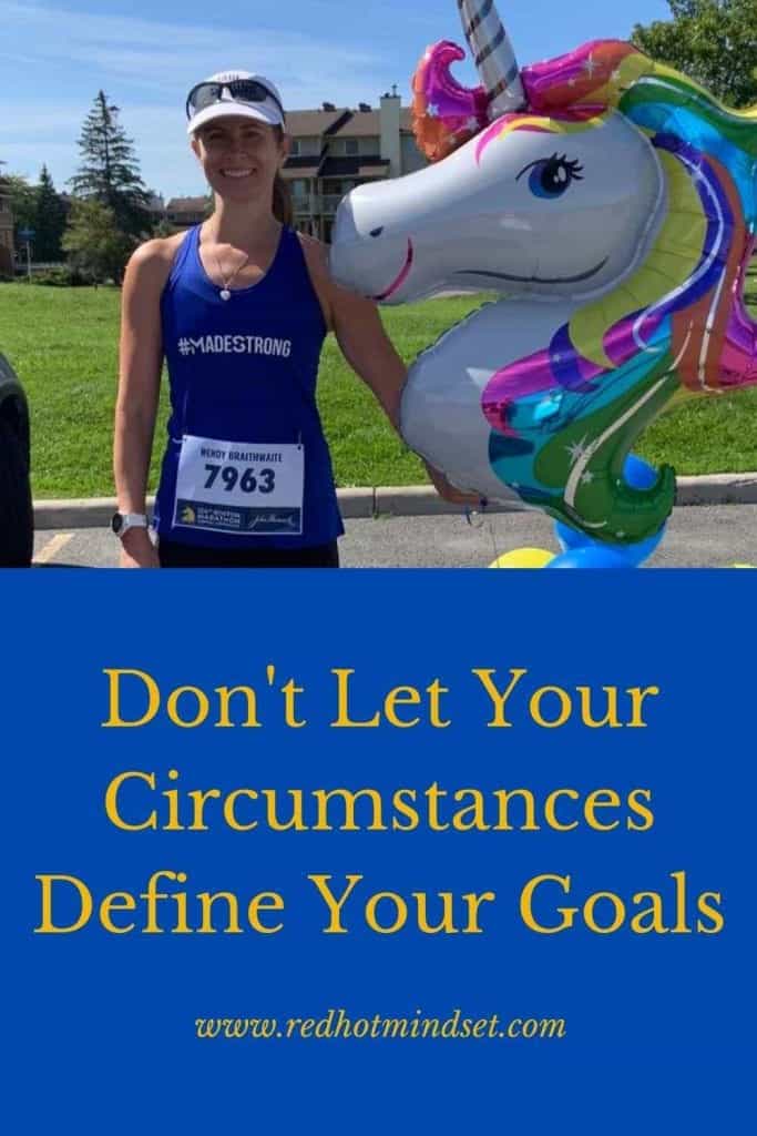 Woman smiling with her hair pulled back and a white visor wearing a blue tank and holding a colorful unicorn balloon after finishing a running race