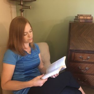 A woman sitting in a chair while reading a book