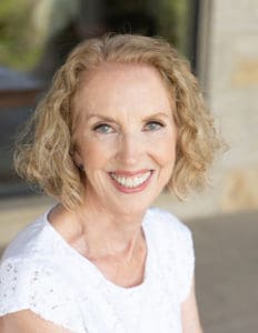 headshot of woman with dirt blond curly hair smiling.