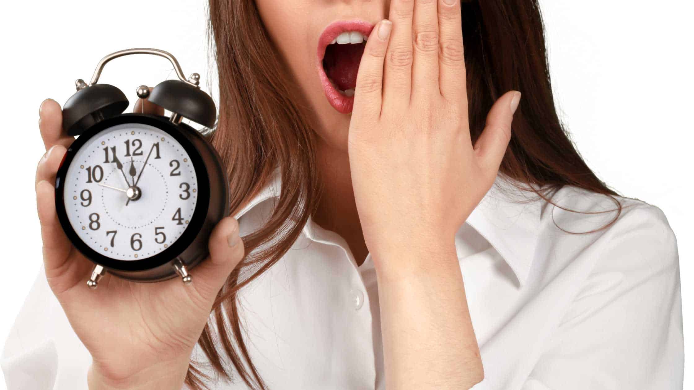 woman with mouth wide open and hand half over her mouth holding a small clock in her opposite hand